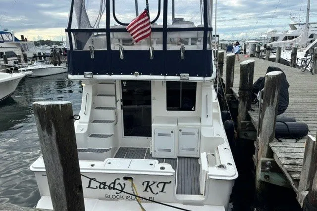 Slide: The Image of 2006 Silverton 34 Convertible docked, featuring rear view with American flag and marina backdrop. - 2