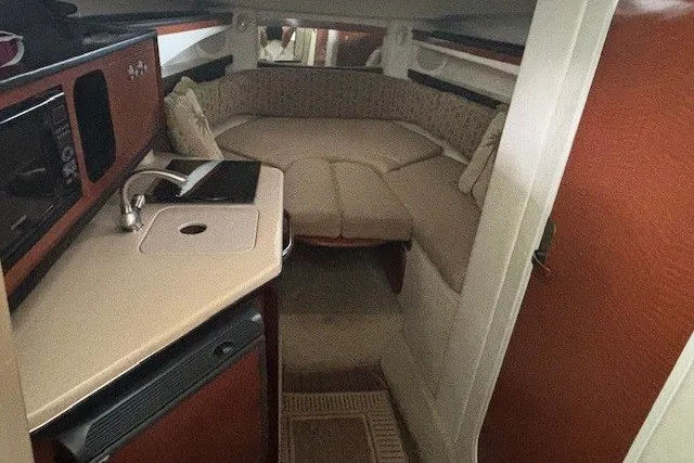 Slide: The Image of Interior of 2005 Sea Ray 270 Amberjack boat with cozy seating and compact kitchenette. - 8