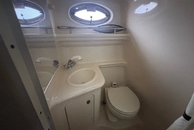 Slide: The Image of 2005 Sea Ray 270 Amberjack boat bathroom with sink, toilet, and oval window. - 9