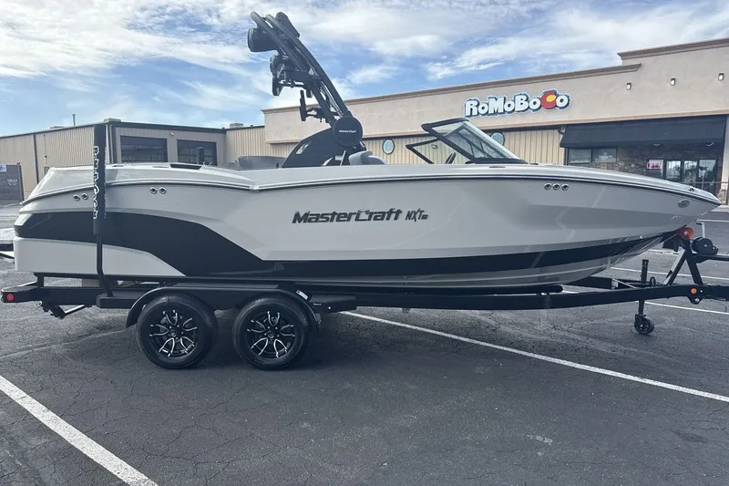 Slide: The Image of A 2027 MasterCraft NXT23 boat on a trailer in a parking lot in front of a building. - 6