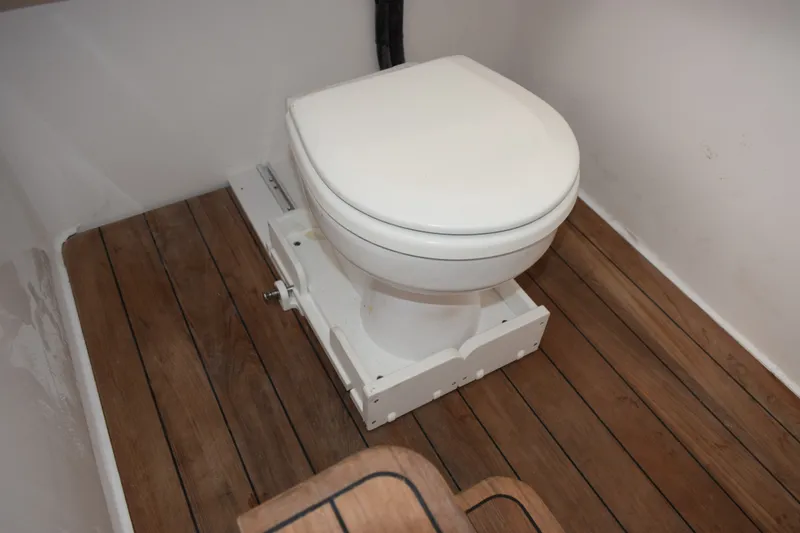 Slide: The Image of Boat bathroom with wooden flooring, featuring a white toilet. Contender 44 ST, 2027 model. - 31