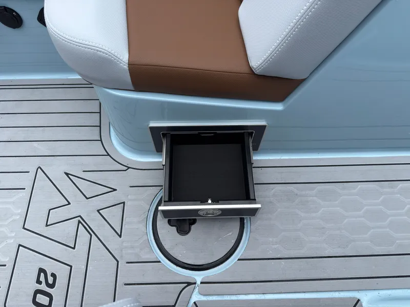 Slide: The Image of An open storage compartment on a boat with gray flooring and a brown seat. - 30