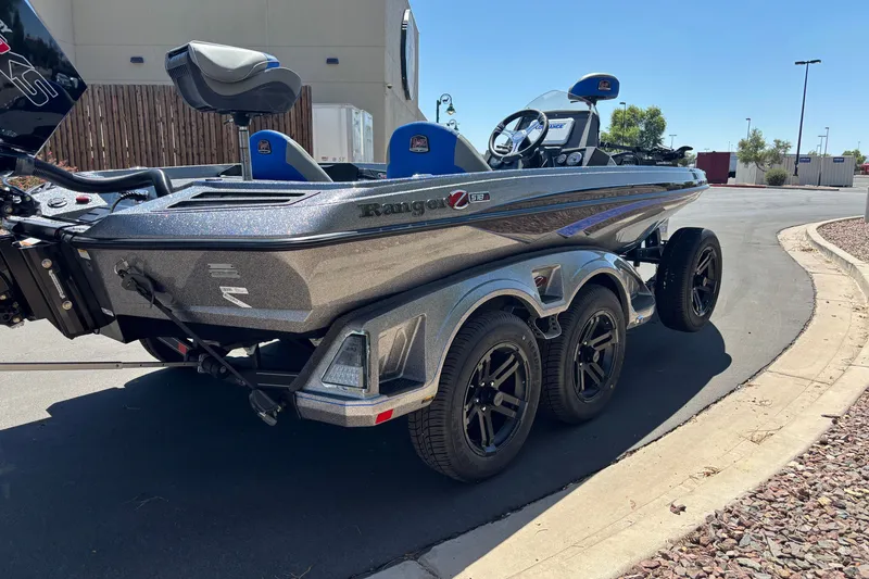 Slide: The Image of 2027 Ranger Z518 Cup-Equipped boat on trailer, parked outdoors, showcasing sleek design and triple-axle wheels. - 5