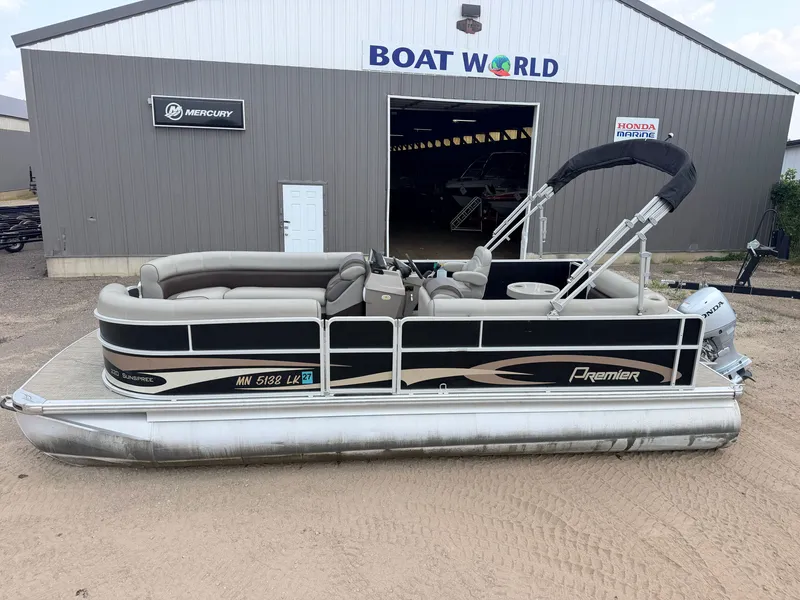 Slide: The Image of A 2016 Premier 220 SunSpree pontoon boat with a 50HP Honda 4-stroke engine, parked outside a boathouse. - 4