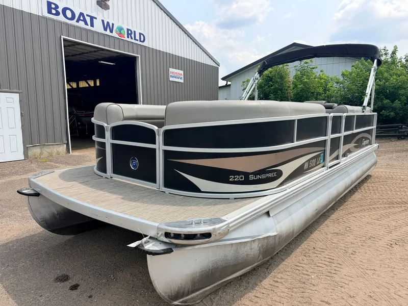 Slide: The Image of A 2016 Premier 220 SunSpree pontoon boat with a 50HP Honda 4-stroke engine, parked outside a boathouse. - 39