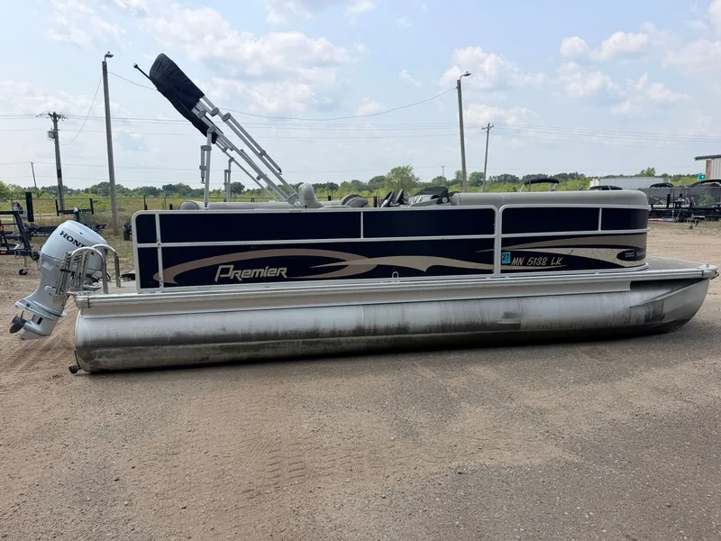 Slide: The Image of A 2016 Premier 220 SunSpree pontoon boat with a 50HP Honda 4-stroke engine, parked on dry land. - 50