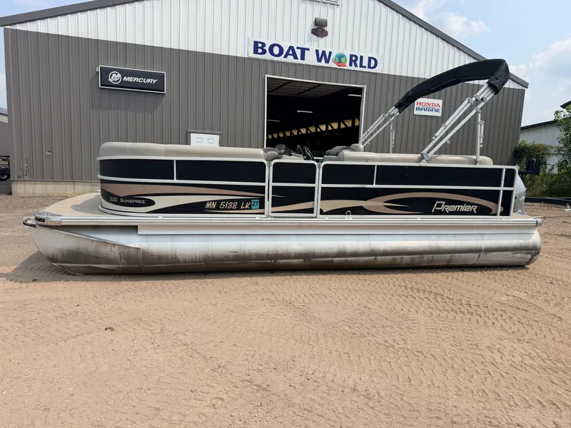 Slide: The Image of A 2016 Premier 220 SunSpree pontoon boat with a 50HP Honda 4-stroke engine, parked outside a boat dealership. - 43