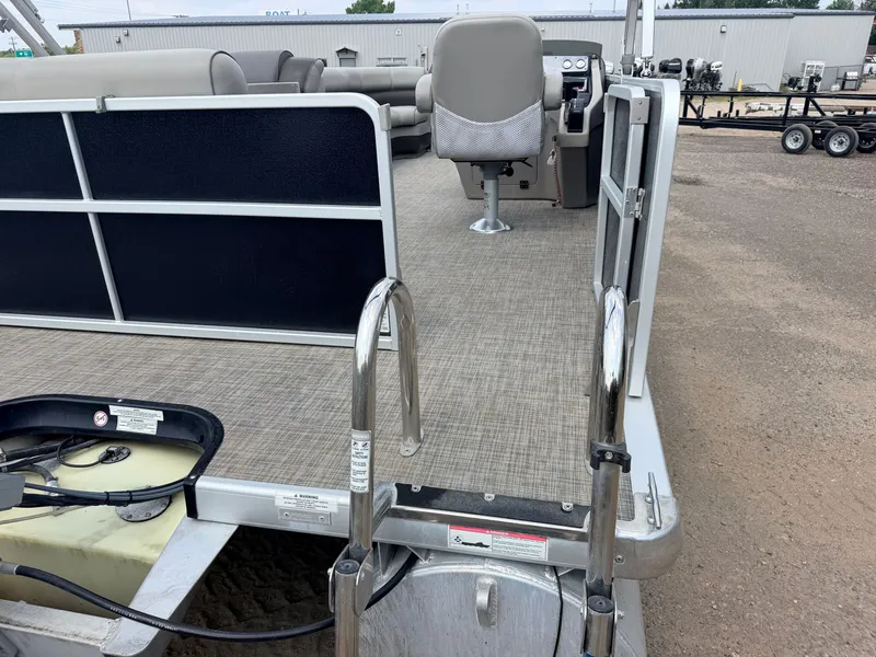 Slide: The Image of A pontoon boat with gray carpeting and a helm station. A ladder leads into the water. - 36