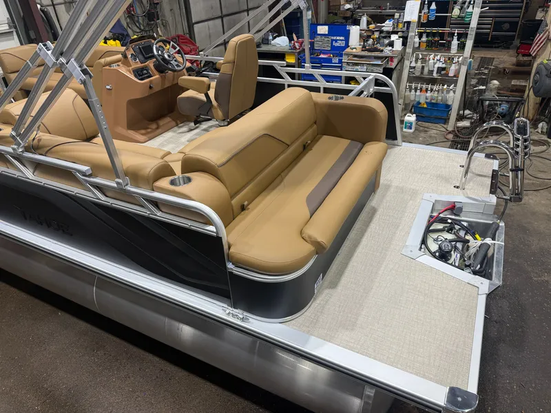 Slide: The Image of A modern pontoon boat with beige seating and silver railing, parked in a workshop. - 4