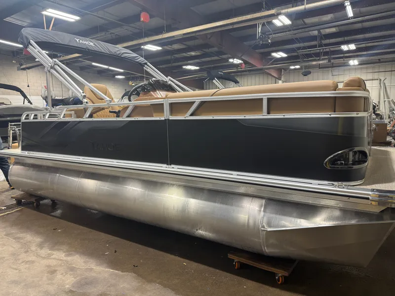 Slide: The Image of A modern pontoon boat with a black hull and beige interior in a warehouse setting. - 41