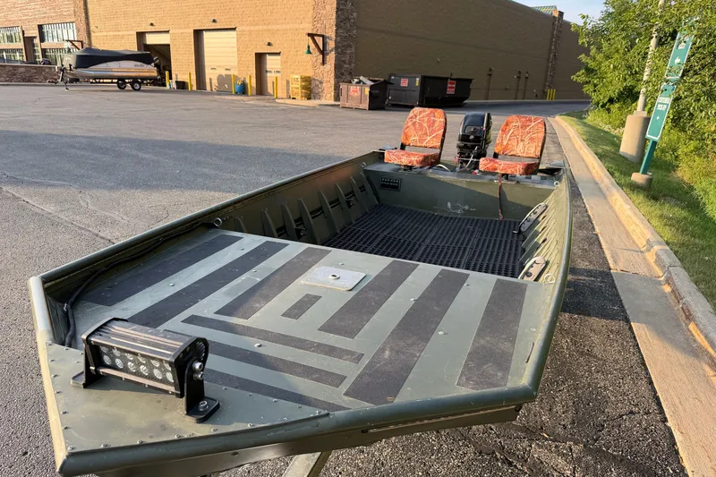 Slide: The Image of 2017 Alumacraft MV 1648 Jon boat with camouflage seats and mounted light, parked outdoors. - 7