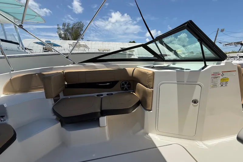 Slide: The Image of 2019 Sea Ray SPX 190 Outboard boat interior with tan seating and windshield under blue sky. - 19
