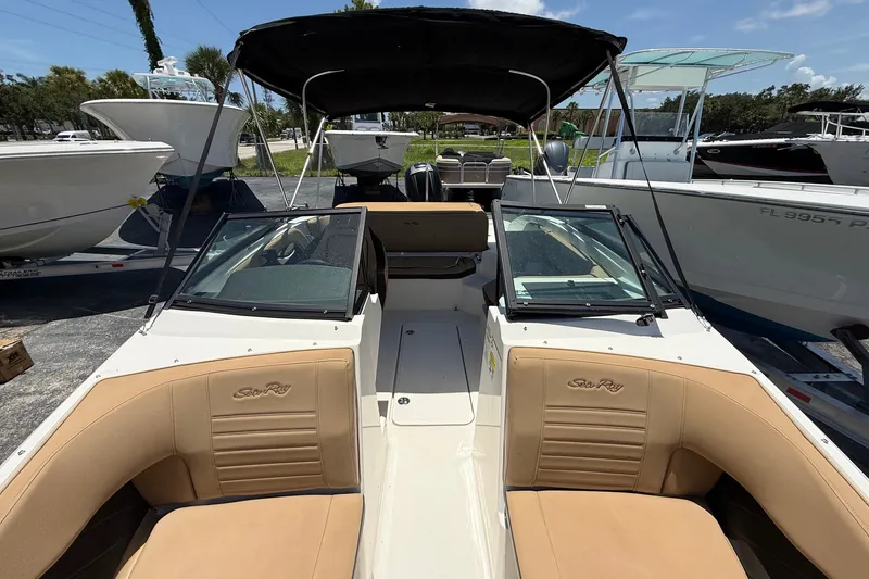 Slide: The Image of 2019 Sea Ray SPX 190 Outboard boat with tan seating and black canopy, docked outdoors. - 15