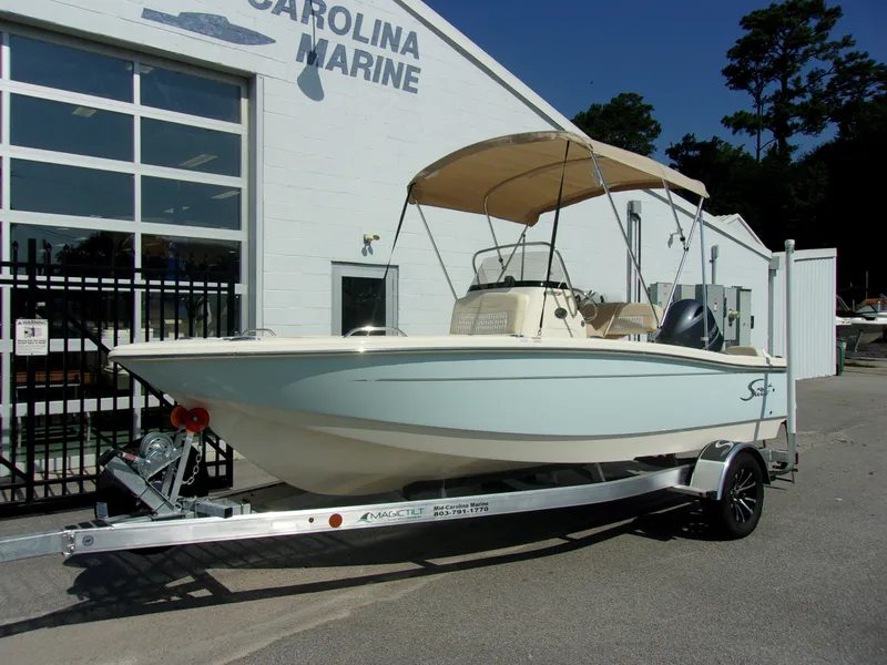 The Image of A 2026 Scout 188 Sportfish boat on a trailer in front of a building. - 1