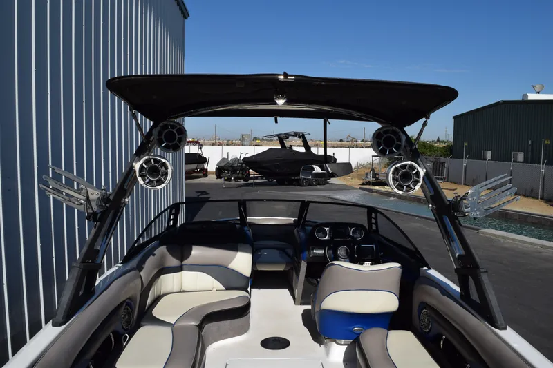 Slide: The Image of 2013 Malibu Wakesetter 23 LSV boat interior with speakers and seating, parked outdoors. - 6