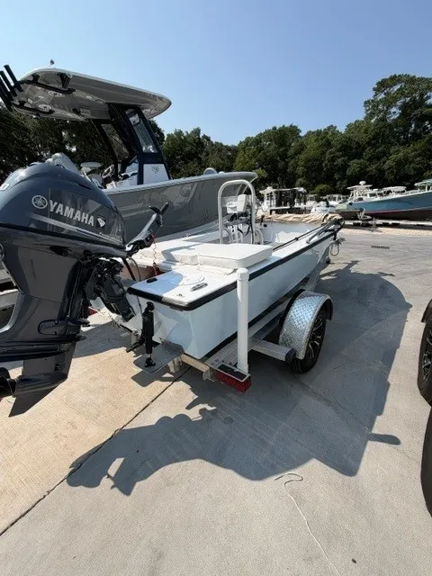 Slide: The Image of A white skiff boat with a Yamaha outboard motor sits on a trailer in a parking area. - 14