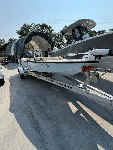 Slide: The Image of A white skiff boat on a trailer, surrounded by other boats in an outdoor storage area. - 10