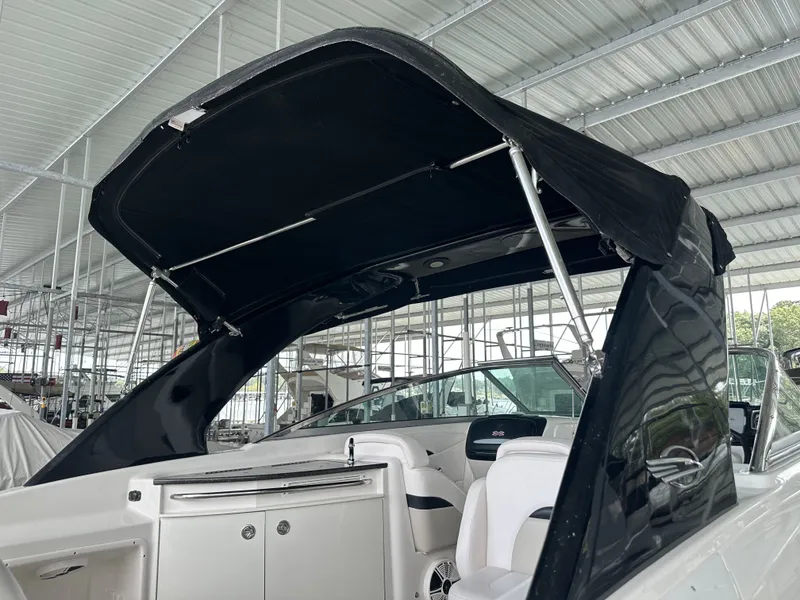 Slide: The Image of A 2011 Chaparral 287 SSX boat with a black bimini top in a covered dock. - 33