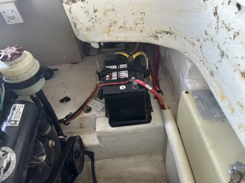 Slide: The Image of A boat engine compartment with a battery, cables, and engine block in a 2011 Chaparral 287 SSX. - 12