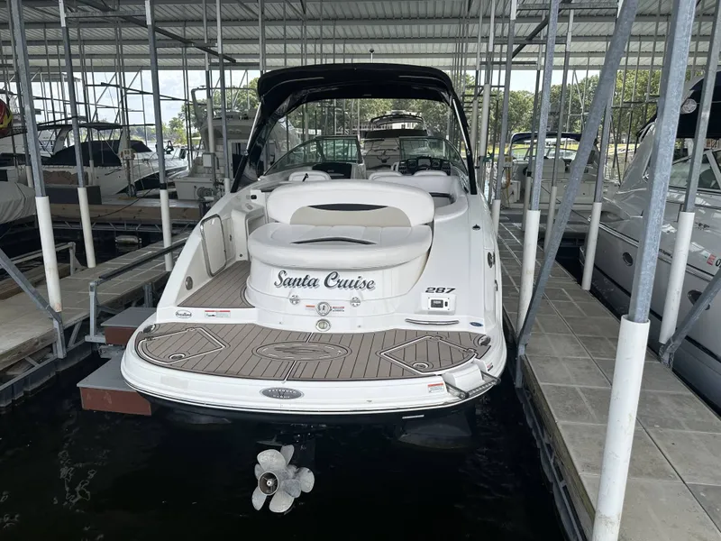 Slide: The Image of A 2011 Chaparral 287 SSX boat is docked under a covered area. It features a white exterior and spacious swim platform. - 35