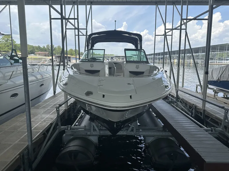 The Image of A 2011 Chaparral 287 SSX boat is docked under a covered area by the water. - 3