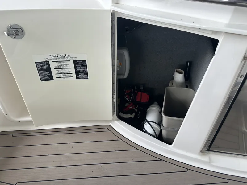 Slide: The Image of An open storage compartment on a boat with various items and a manual on the door. - 14
