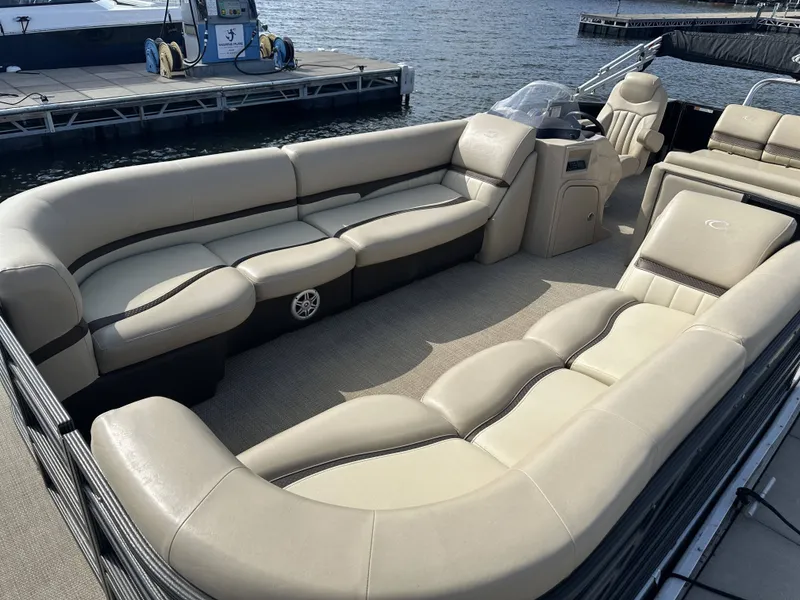 Slide: The Image of A sleek pontoon boat with beige upholstered seating and a helm station, docked at a pier. - 3