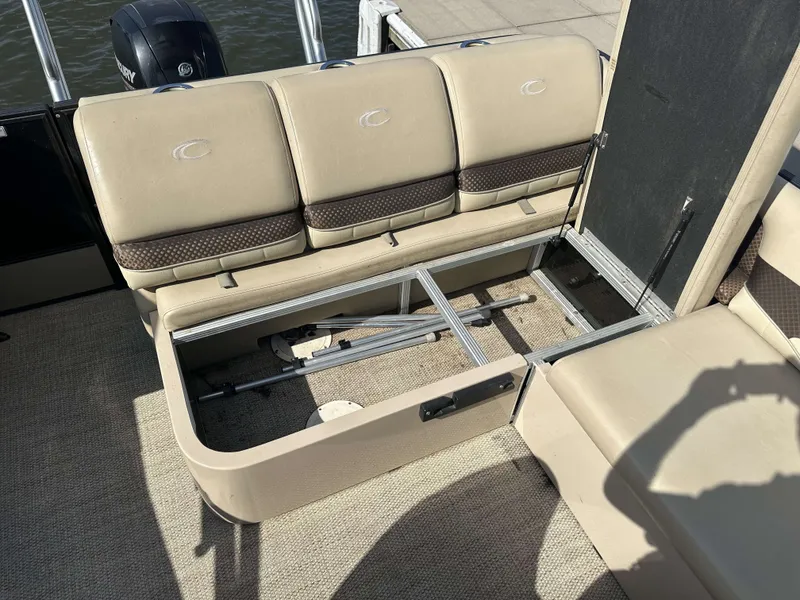 Slide: The Image of An open storage compartment under boat seats, featuring beige upholstery and a motor in the background. - 30