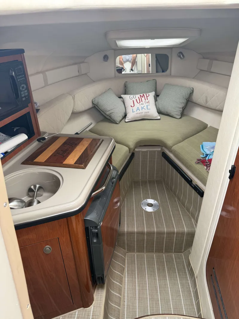 Slide: The Image of Interior of a 2007 Sea Ray 240 Sundancer with a kitchenette and seating area. - 12