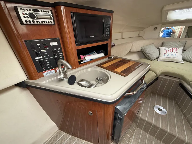 Slide: The Image of The cabin of the 2007 Sea Ray 240 Sundancer features a compact kitchenette with a sink and microwave. - 15