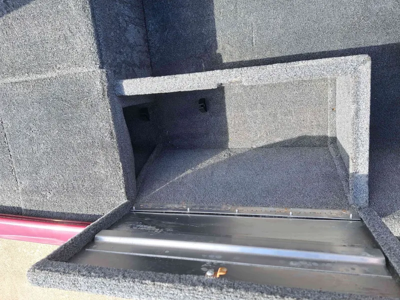 Slide: The Image of An open storage compartment on a boat with gray carpeting. - 6