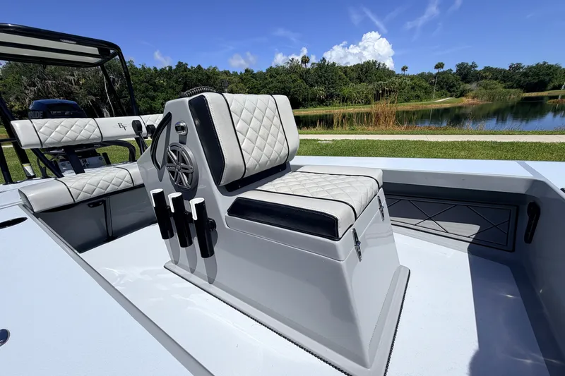 Slide: The Image of 2019 Beavertail Skiffs Vengeance 18' boat interior with quilted seating near a scenic lake. - 32