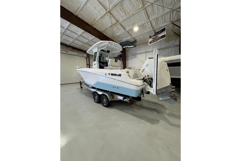 Slide: The Image of 2026 Wellcraft 243 Fisherman boat in a showroom, rear view. - 1