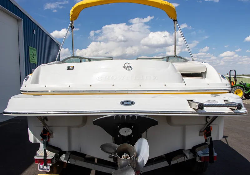 Slide: The Image of A 2008 Crownline 210 LS boat with a yellow sunshade, on a trailer in front of a building. - 4