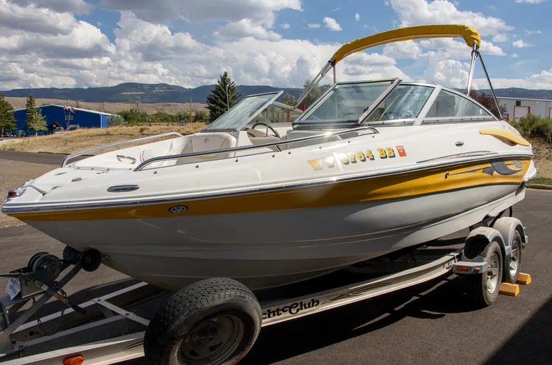 Slide: The Image of A 2008 Crownline 210 LS boat on a trailer, featuring yellow accents and a Bimini top. - 3
