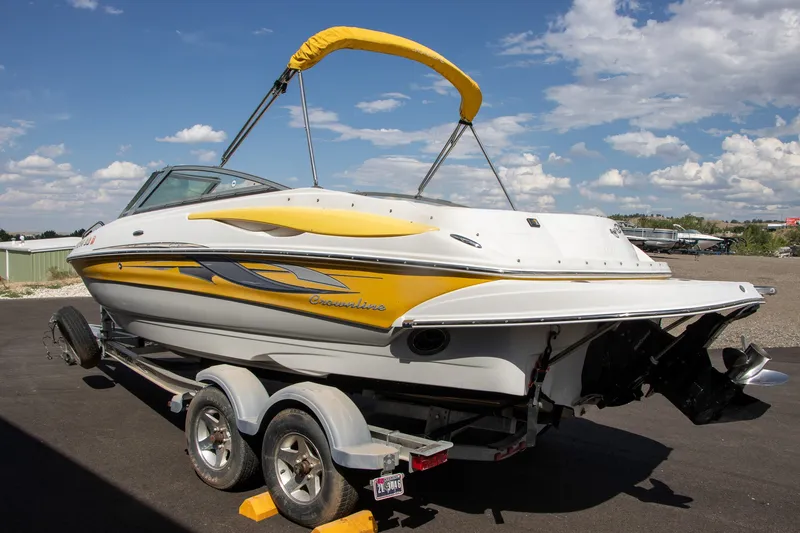 Slide: The Image of A 2008 Crownline 210 LS boat on a trailer, featuring yellow accents and a Bimini top. - 2