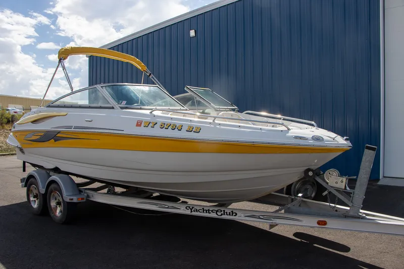 Slide: The Image of A 2008 Crownline 210 LS boat on a trailer, featuring yellow accents and a blue building in the background. - 6