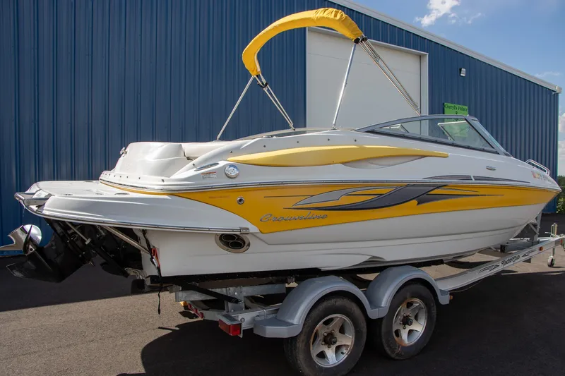 Slide: The Image of A 2008 Crownline 210 LS boat with yellow accents, on a trailer in front of a blue building. - 5