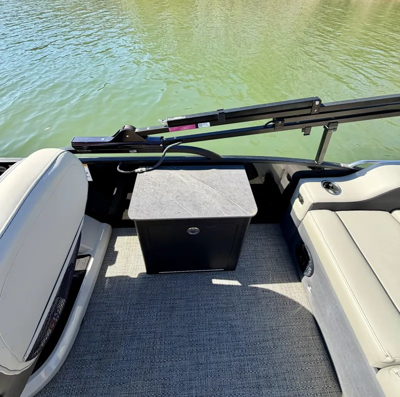 Slide: The Image of The image shows the interior of a 2024 Barletta Cabrio 24 UE. There are comfortable seats and a small table on a carpeted floor. The boat is on calm water. - 7