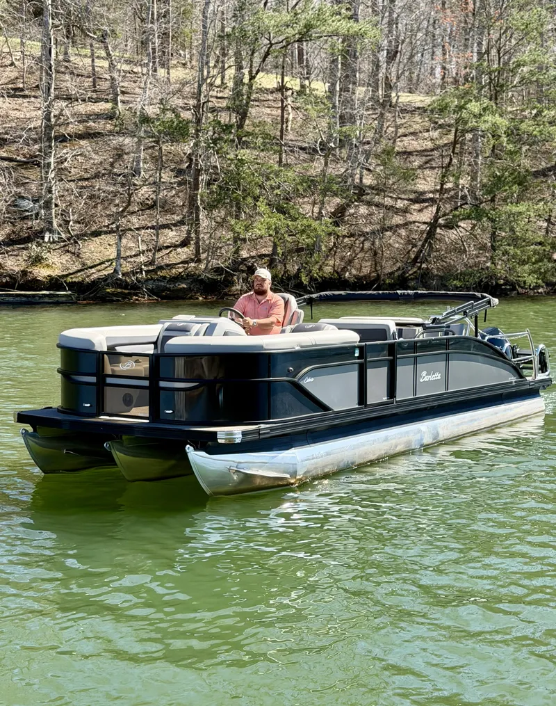 Slide: The Image of A man operates a Barletta Cabrio 24 UE pontoon boat on a calm lake. - 4