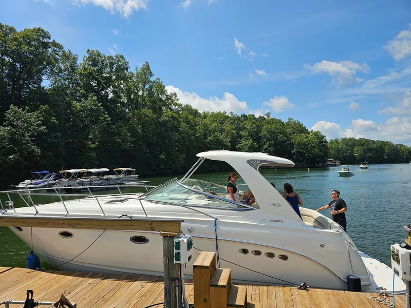The Image of A white 2011 Chaparral 370 Signature boat docked at a wooden pier. People are on board. - 1