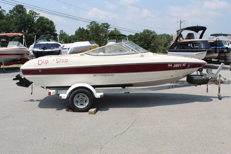 Slide: The Image of A white and red 2012 Stingray 185 LS boat on a trailer in a parking lot. - 6