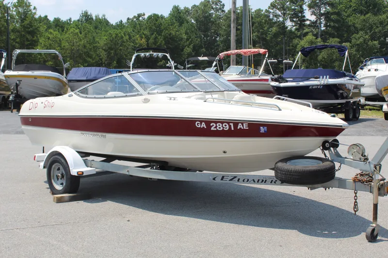Slide: The Image of A white and red 2012 Stingray 185 LS boat on a trailer in a marina area. - 7