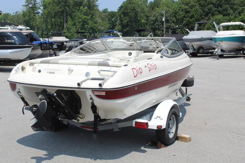 Slide: The Image of A white and red 2012 Stingray 185 LS boat on a trailer in a parking lot. - 8