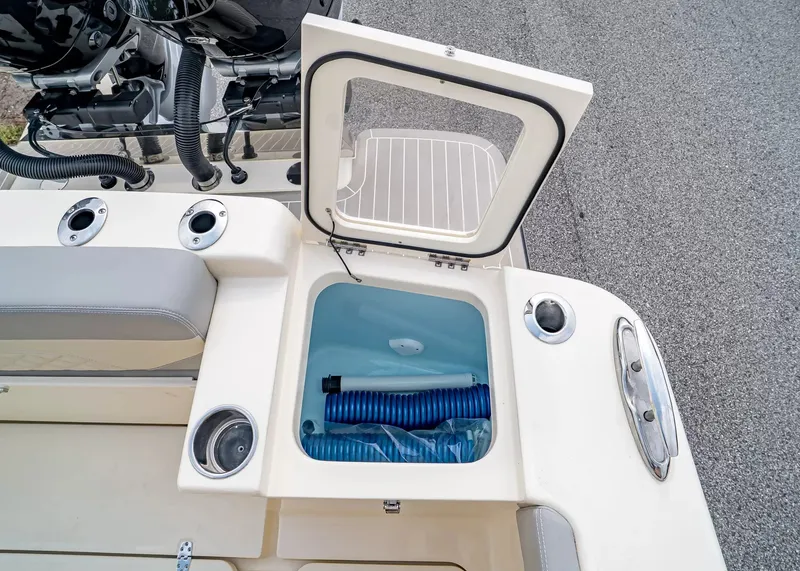 Slide: The Image of An open storage compartment on a Scout 330 LXF boat reveals a blue hose and cup holders. - 11