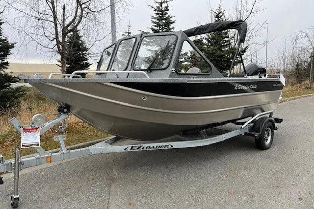 Slide: The Image of 2024 Spartan 185 Astoria boat on EZ Loader trailer, parked on roadside. - 0