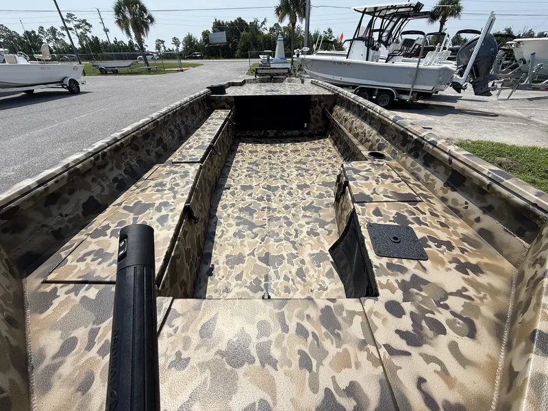 Slide: The Image of An Excel Viper F4 1751 aluminum boat with camouflage pattern, parked on a trailer, surrounded by other boats. - 5