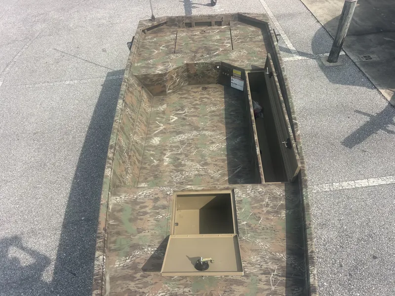 Slide: The Image of A rugged boat with camouflage pattern, open seating area, and storage, parked on a lot. - 3