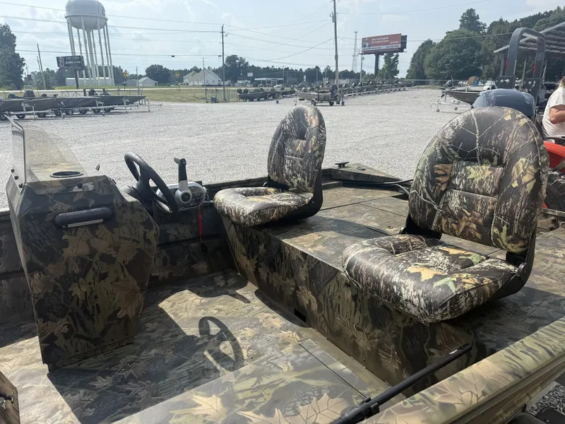 Slide: The Image of The image shows a Lowe Roughneck 1650SC boat with camo-patterned seats in a parking area. - 5