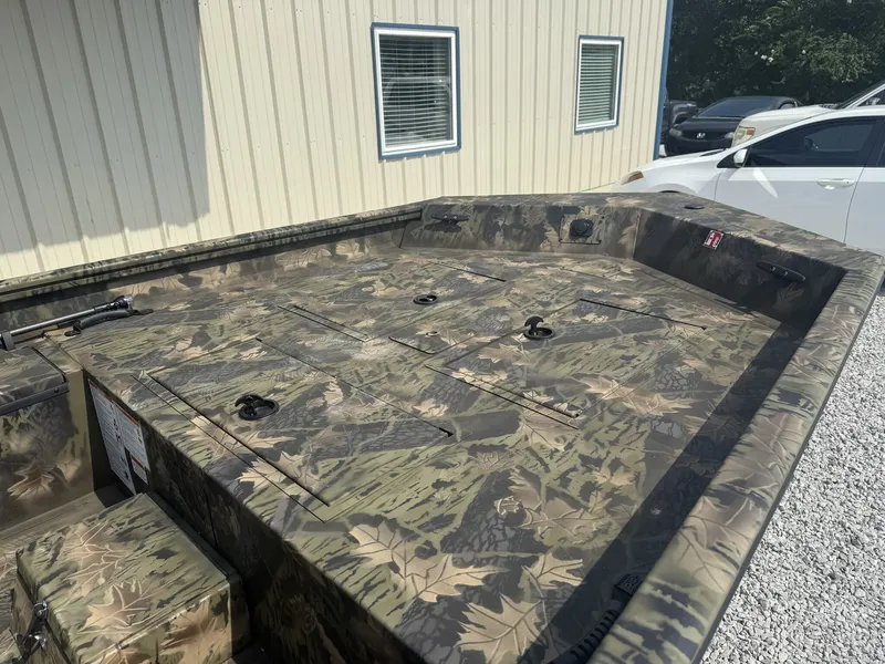 Slide: The Image of The image shows a Lowe Roughneck 1650SC boat with camouflage pattern, parked on a gravel lot. - 3